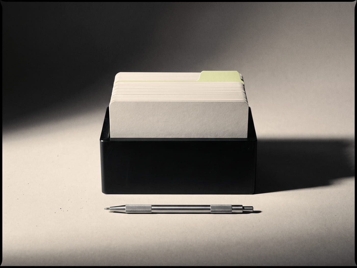 Blank filing cards standing in a machined aluminium index holder, one card drawn proud of the rest